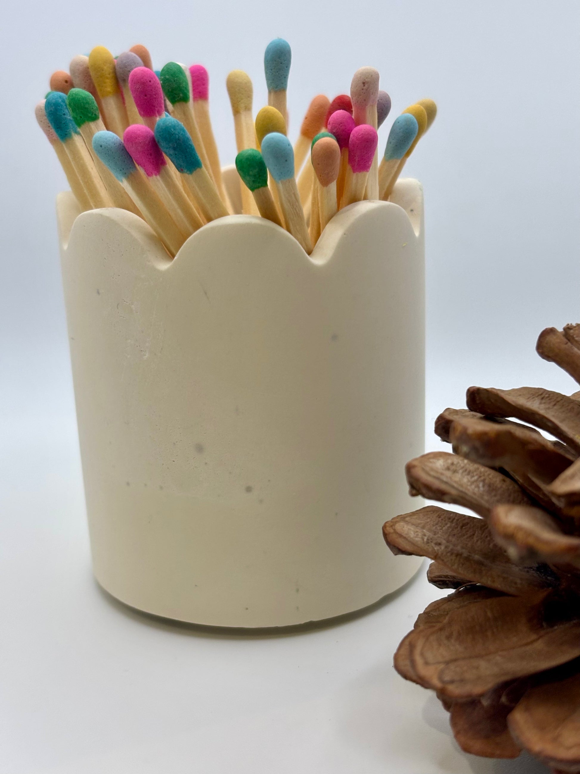 Pot à allumettes artisanal posé sur une table, montrant le grattoir intégré discrètement placé sous le pot